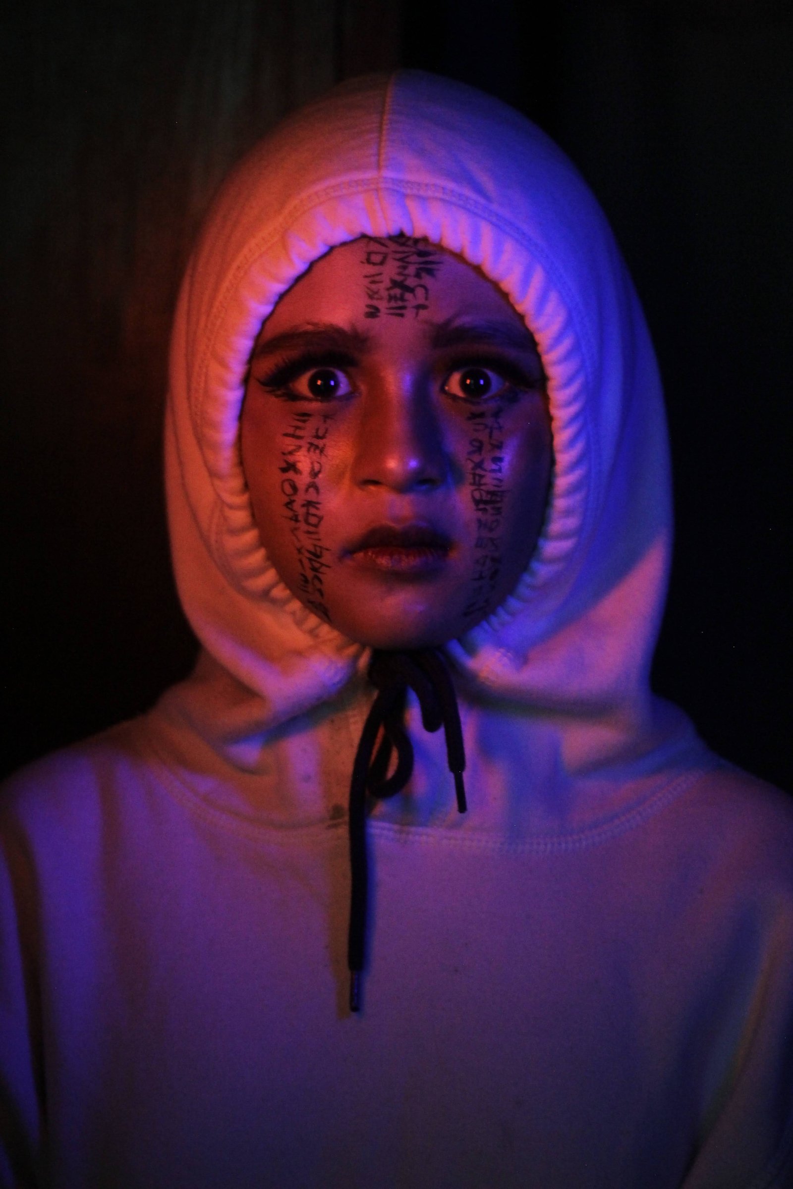 Portrait of a person in a hoodie under neon light