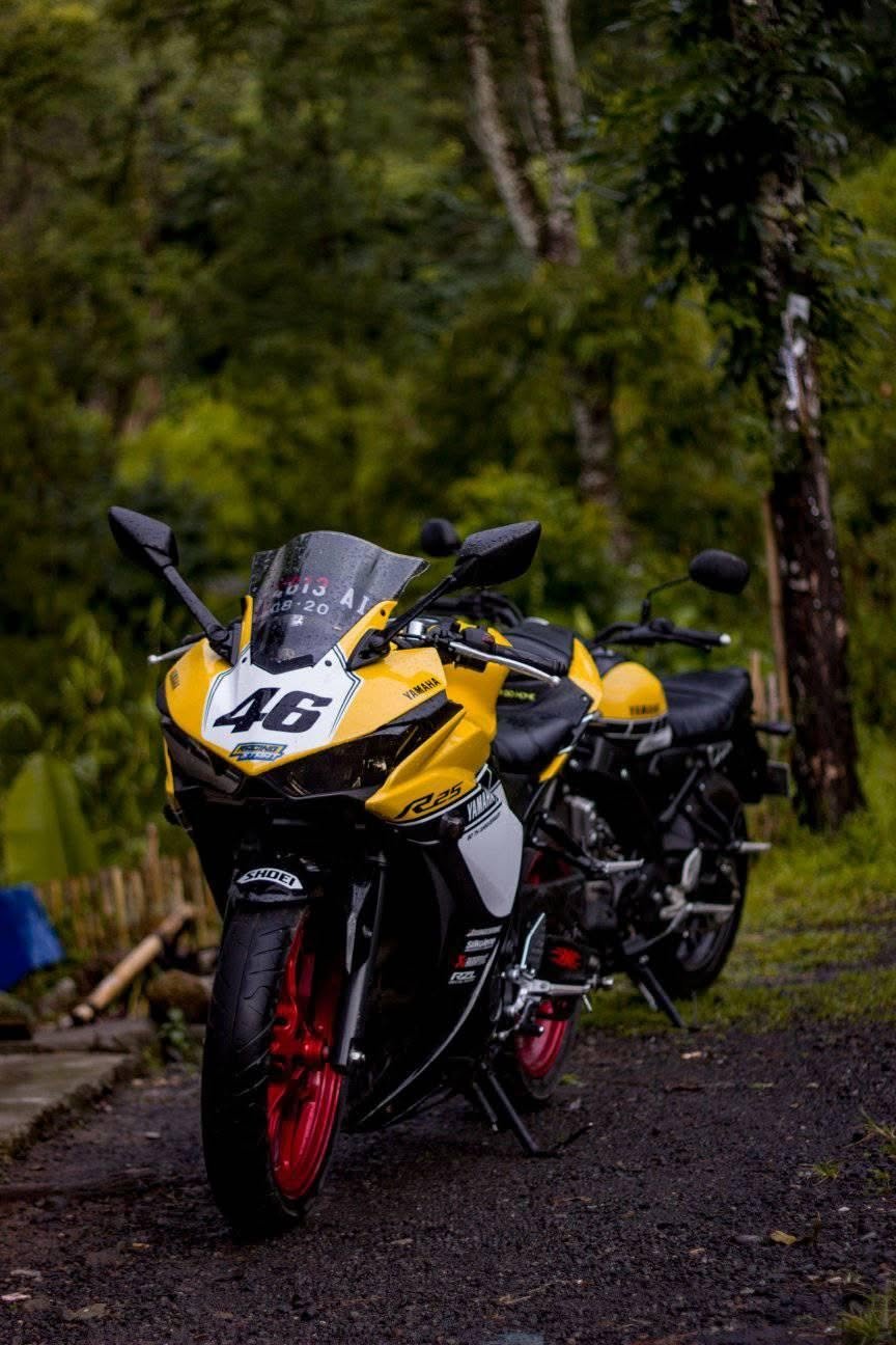 A yellow sport bike with the number 46 parked on a wet forest road